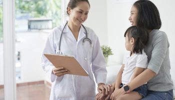 Male pediatrician reassuring mother of little Asian girl